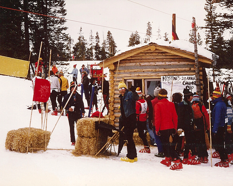 The HooDoo Timing House ('Peter-built' log cabin) after the Keystone Invitational Challenge Cup II, March 1975. Jack McGeehan (wearing a yellow hat and boots) gives a thumbs-up for a well-done event | Photo: Bruce Schaefer