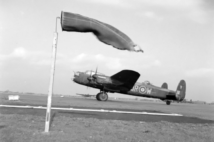 Windsocks: a RAF Avro Lancaster World War II heavy bomber taxying past the wind cone at Coningsby, Lincolnshire | Photo: IWM
